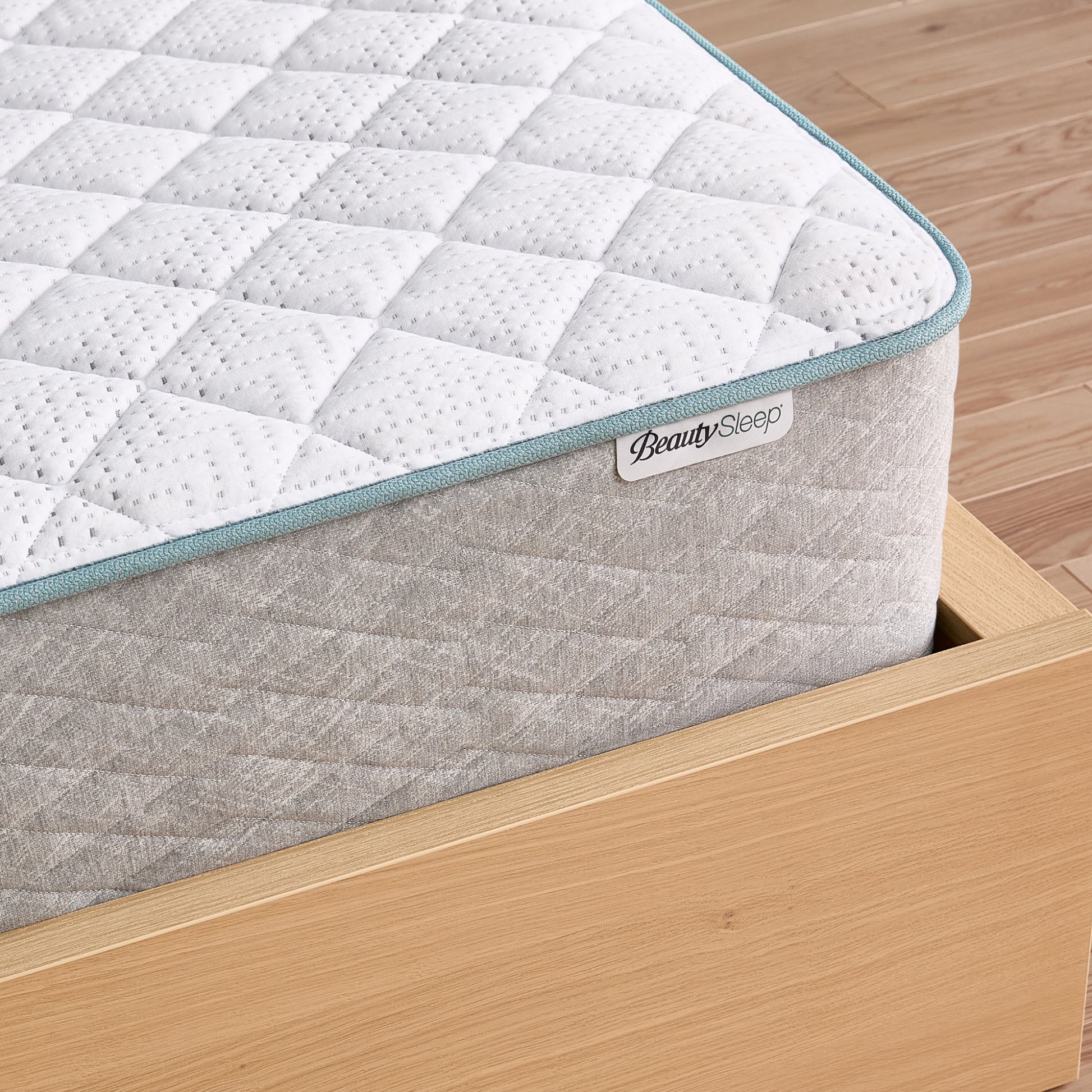 Gray and white mattress with 'BeautySleep' logo on a wooden bed frame.