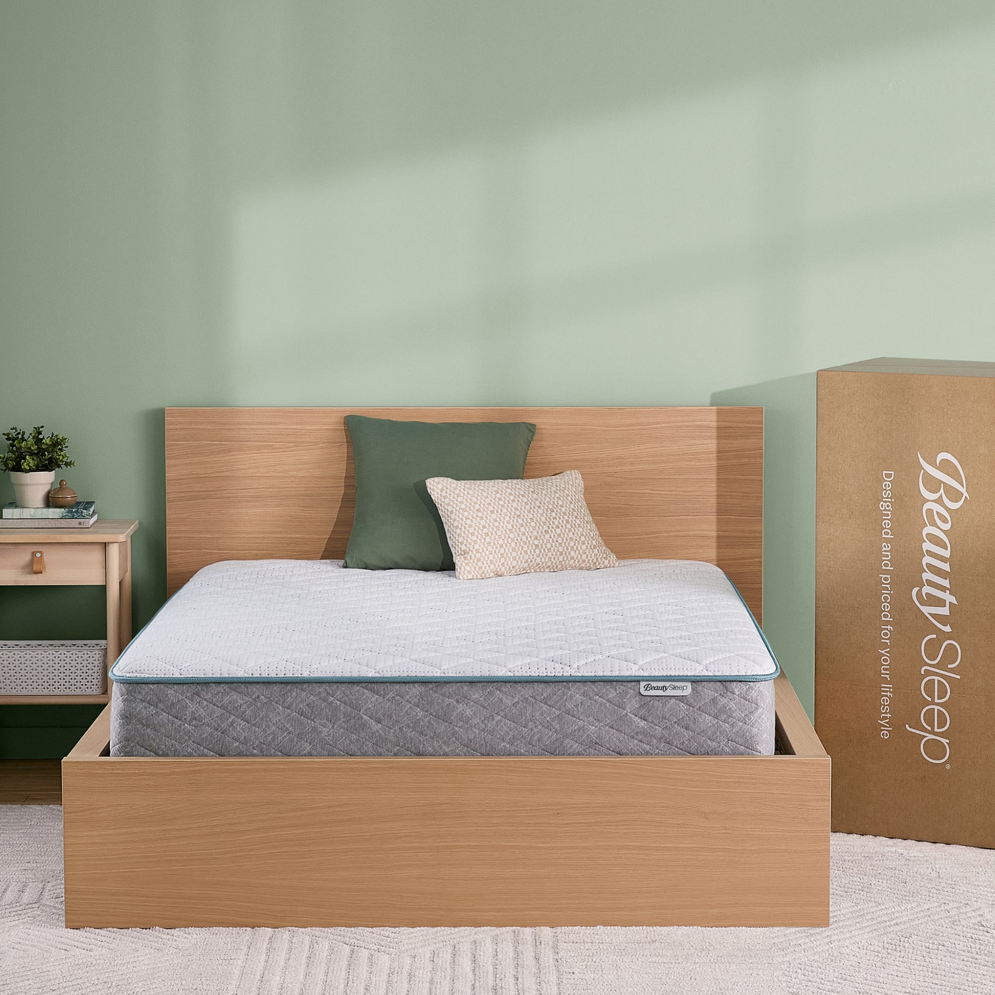 BeautySleep Mattress with Wooden bed frame and pillows in a room setting, next to a 'Beauty Sleep' branded box.